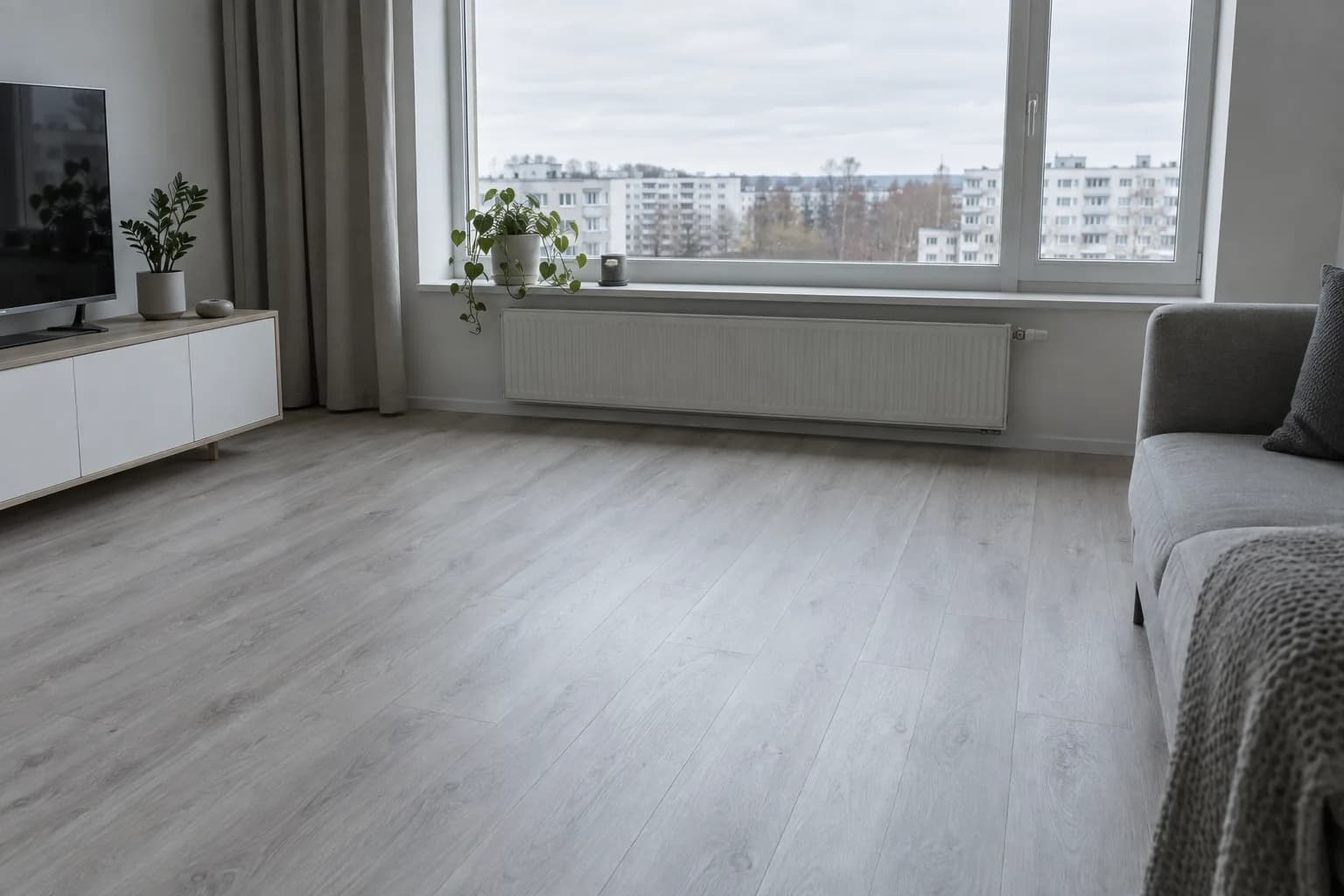 Hall tammeimitatsiooniga laminaatpõrand paneelmaja korteri elutoas, suur aken